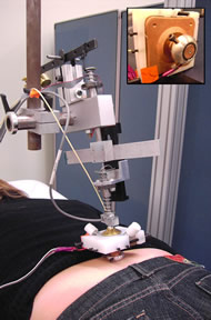 This photograph shows a subject lying prone on the mat table, and the indenter is attached to the sacrum skin for testing.  The small picture shows the close look of indenter head. 